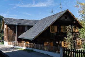 uma grande casa de madeira com um telhado preto em Chalet Schmelz Huette mit Sauna und Garten em Flattach