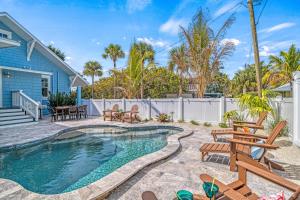 a backyard with a swimming pool and chairs and a house at Salty Sister - 302 in Anna Maria