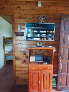 a television on top of a wooden wall with a cabinet at CABAÑA AKAPANA in Huerta Grande