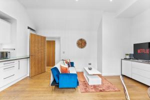 a living room with a blue chair and a tv at Beautiful Central Canterbury Apartment - Large Balcony in Kent