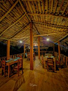 a restaurant with wooden tables and chairs and a roof at River Edge Safari Cottage in Udawalawe