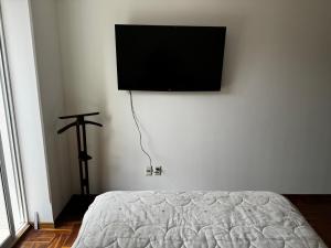 a bedroom with a bed and a flat screen tv on the wall at Dormitorio en San Miguel in La Paz