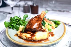a plate of food with meat and vegetables on a table at The George Hotel in Pangbourne