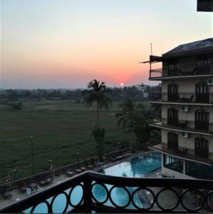a building with a swimming pool in front of a sunset at Blue Flamingo Goa Apartment-Casa-Baga in Baga