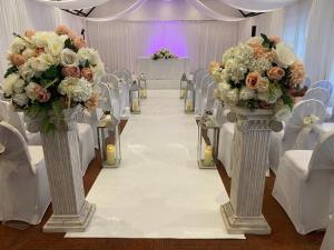 un pasillo de bodas con flores y sillas blancas y rosas en The George Hotel Pangbourne, en Pangbourne