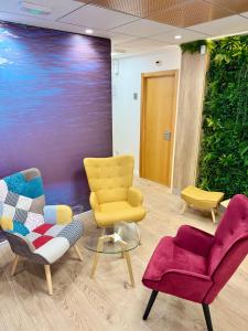 una sala de espera con sillas, mesas y una planta en Residencia Mediterraneo en San Vicente del Raspeig