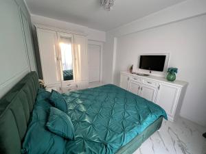 a living room with a green bed and a television at Luxe Central Apt: Free Parking in Oradea