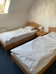 two twin beds in a room with two tables at Penzion BeSeDa in Bratronice