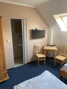 a room with a bed and two chairs and a television at Penzion BeSeDa in Bratronice
