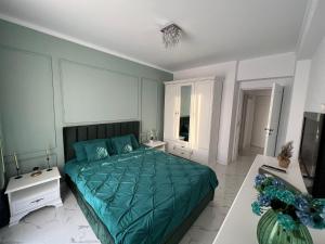a bedroom with a bed with a green comforter at Luxe Central Apt: Free Parking in Oradea