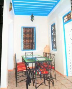 una mesa y sillas en una habitación con techo azul en Dar Rita, en Houmt El Souk