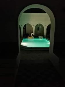una piscina con un cisne en una habitación en Dar Rita, en Houmt El Souk