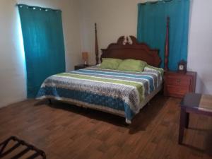 1 dormitorio con 1 cama grande y cortinas azules en Garden house, 1 km de pradera chiquimula en Chiquimula