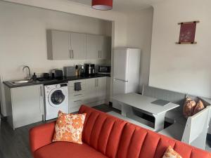 a living room with a red couch and a kitchen at 1 Bed Apartment Sleeps 3, Ferryhill Near Durham & WiFi in Ferryhill