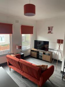 a living room with a red couch and a flat screen tv at Quirky and Cosy Self Contained Flat, Ferryhill Near Durham in Ferryhill