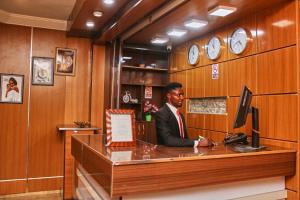 a man in a suit sitting at a desk at GLAMOUR PARK'S HOTEL, ABUJA in Abuja
