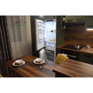 a kitchen with a wooden table and an open refrigerator at Gallery Apartman in Győr +14 photos