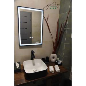 ein Badezimmer mit einem weißen Waschbecken und einem Spiegel in der Unterkunft Gallery Apartman in Győr
