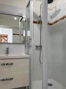 baño blanco con ducha y lavamanos en Au Bonheur Dezange en Pézenas