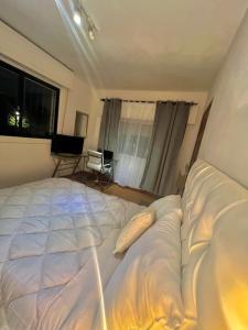 a bedroom with a large white bed in front of a window at Habitacion en Carrasco Sur, cerca del aeropuerto y la rambla in Montevideo