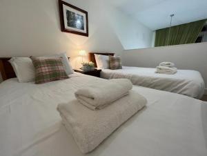 1 dormitorio con 2 camas y toallas. en The Classrooms, Loch Ness Abbey - 142m2 Lifestyle & Heritage apartment - Pool & Spa - The Highland Club - Resort on lake shores en Fort Augustus