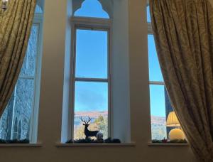 una finestra con la statua di un cervo al centro di The Classrooms, Loch Ness Abbey - 142m2 Lifestyle & Heritage apartment - Pool & Spa - The Highland Club - Resort on lake shores a Fort Augustus