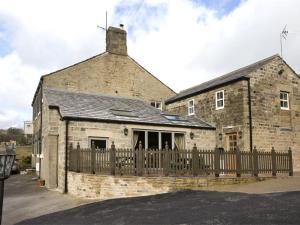 um antigo edifício de tijolos com uma cerca de madeira em 1 Bed in Pateley Bridge G0015 em Pateley Bridge