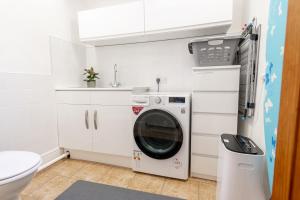 a washer and dryer in a bathroom with a toilet at Mae Cottage in Richmond