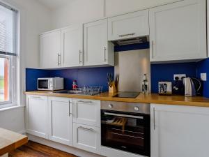 uma cozinha com armários brancos e um forno com placa de fogão em 1 Bed in Bude 78610 em Bude