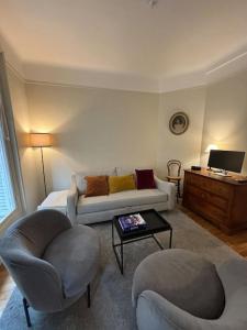 uma sala de estar com um sofá e duas cadeiras em Élégance Parisienne pour 4 personnes em Paris