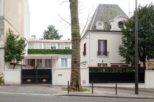 uma casa branca com uma cerca preta e uma árvore em Nets Inn Apartments - Buttes Chaumont D em Paris