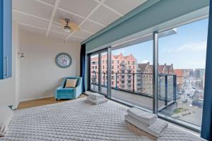 a bedroom with a large window with a blue chair at Staywin Prime Apartments Chmielna in Gdańsk
