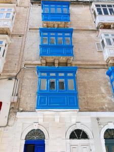 een gebouw met blauwe ramen aan de zijkant bij San Francisco Studios Valletta in Il-Furjana