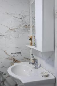 a white bathroom with a sink and a mirror at Sonorus Apartment in Korçë