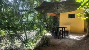 dos sillas y una sombrilla delante de una casa en ÓTIMA NOTA - CASA DO RIO DE PEDRAS Próximo Praias , Ilhas ,Cachoeiras e Centro Histórico en Parati