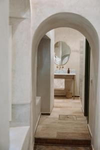 een boog die leidt naar een badkamer met een wastafel en een spiegel bij Riad Le Sable Vert in Marrakesh