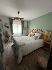 a bedroom with a large white bed and wooden floors at Maison « l’effet-mère »en rez de chaussée  in Aigues-Mortes