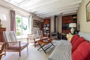 ein Wohnzimmer mit einem roten Sofa und Stühlen in der Unterkunft Sejour detente en famille avec piscine in Andernos-les-Bains