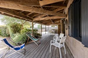 eine Holzterrasse mit Stühlen, einem Tisch und Stühlen in der Unterkunft Sejour detente en famille avec piscine in Andernos-les-Bains
