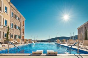 a large swimming pool with chairs and a building at The Chedi Luštica Bay in Tivat
