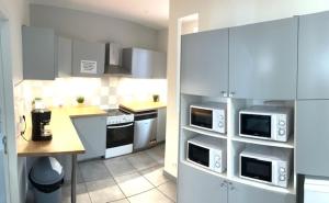 a kitchen with white cabinets and appliances and a counter at Belle et agréable maison de ville 9 chambres in Saint-Étienne