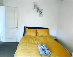 a yellow bed with two pairs of slippers on it at Modern One Bed Apartment Greenwich in London