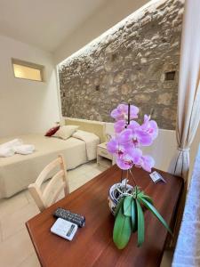 Una habitación con una mesa con un jarrón de flores. en B&B Evelyne en Taormina
