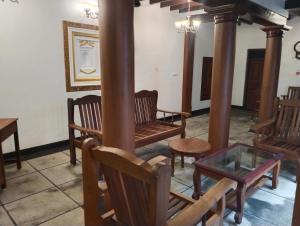 a room with wooden chairs and a glass table at Rebel de Pondiche'ry in Pondicherry