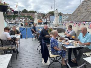 grupa ludzi siedzących przy stołach na pokładzie w obiekcie Lantana Guest House w mieście Weymouth
