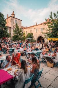 a group of people sitting at tables in a courtyard at Appartement 4 pers1 chb Résidence du Lac vue sur les bois in Monflanquin