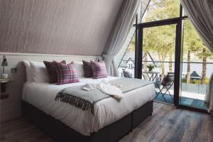 a bedroom with a large bed and a large window at Ardlui Retreat Lodge 4 in Arrochar