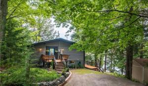 a cabin in the woods with a porch and chairs at Alpine Lake House - Waterfront on Lake Muskoka in Port Carling