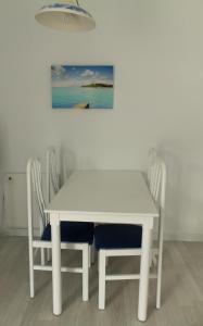 a white table and chairs with a painting on the wall at BLUESEA Anba Romaní in Cala Millor