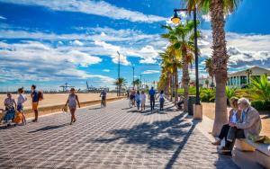 a group of people walking on a sidewalk near the beach at Valencia beach rooms in Valencia